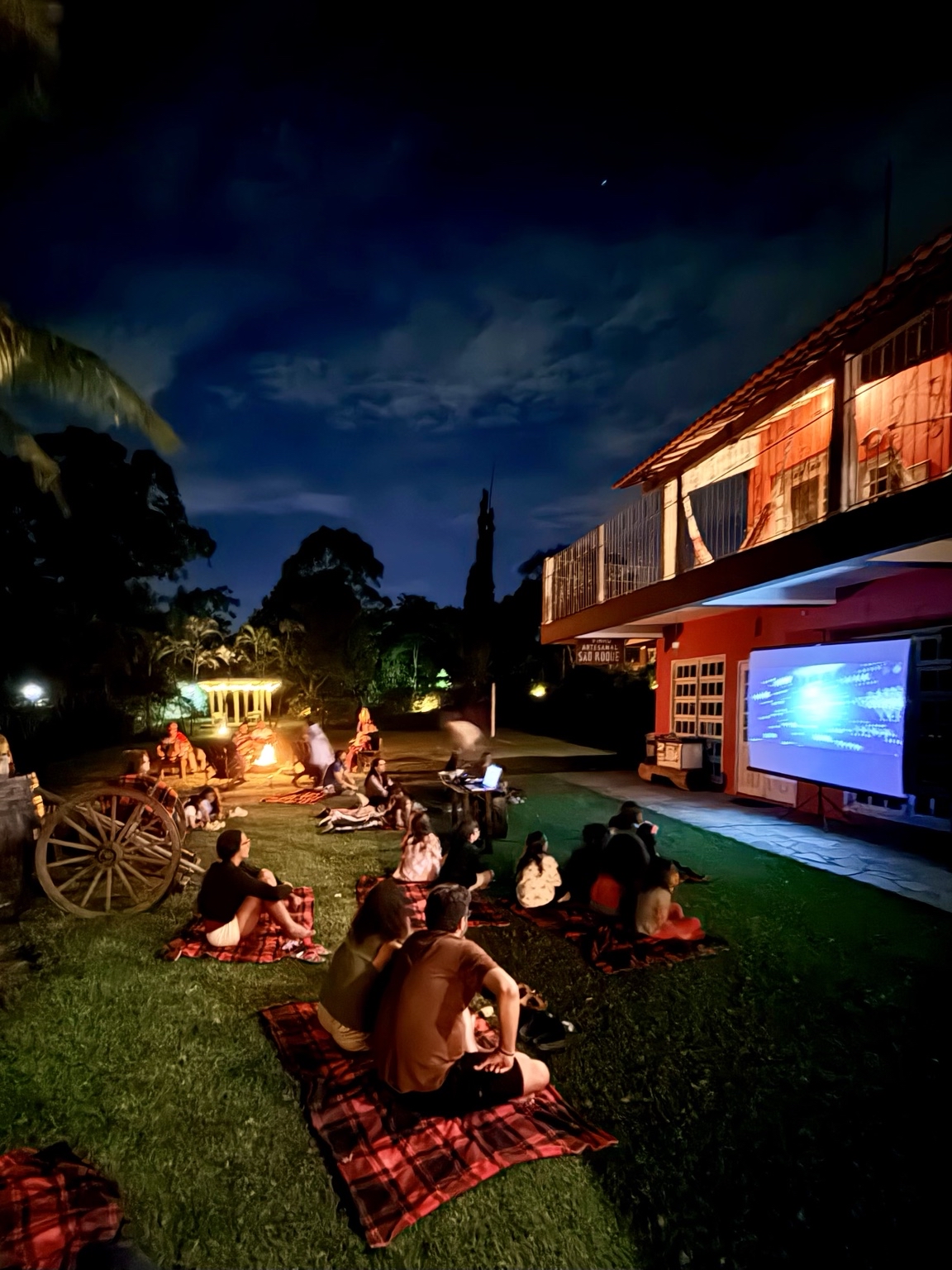 Famílias reunidas no gramado para o cinema ao ar livre da Aldeia